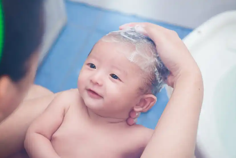 Mãe lavando o cabelo do bebê no banho.