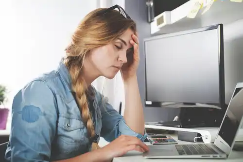 Menina com dor de cabeça na frente da tela do computador